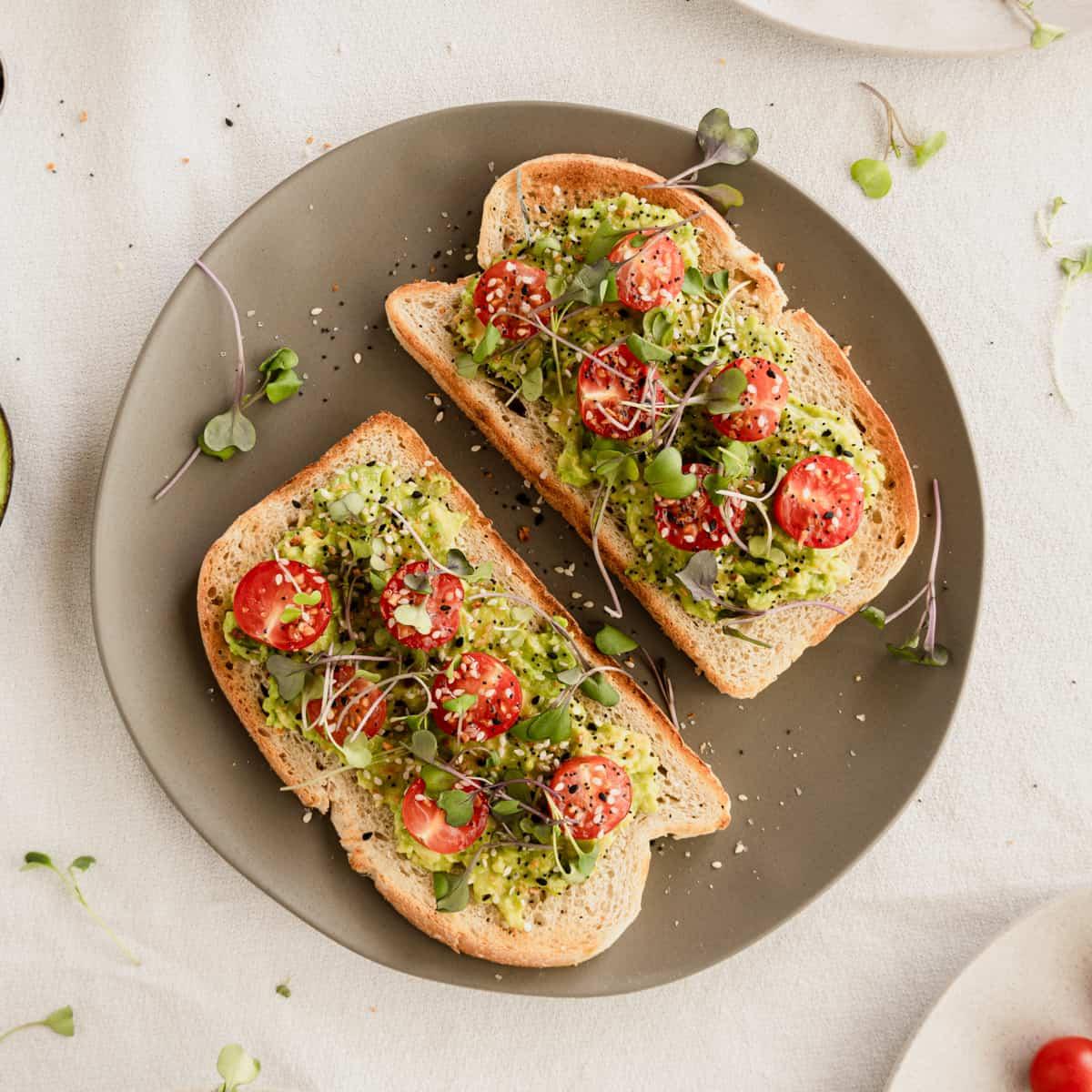 A slice of perfectly toasted bread topped with mashed avocado, everything bagel seasoning, and a side of vibrant salsa.