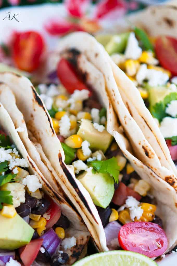 A rustic scene of friends enjoying grilled corn and black bean tacos outdoors