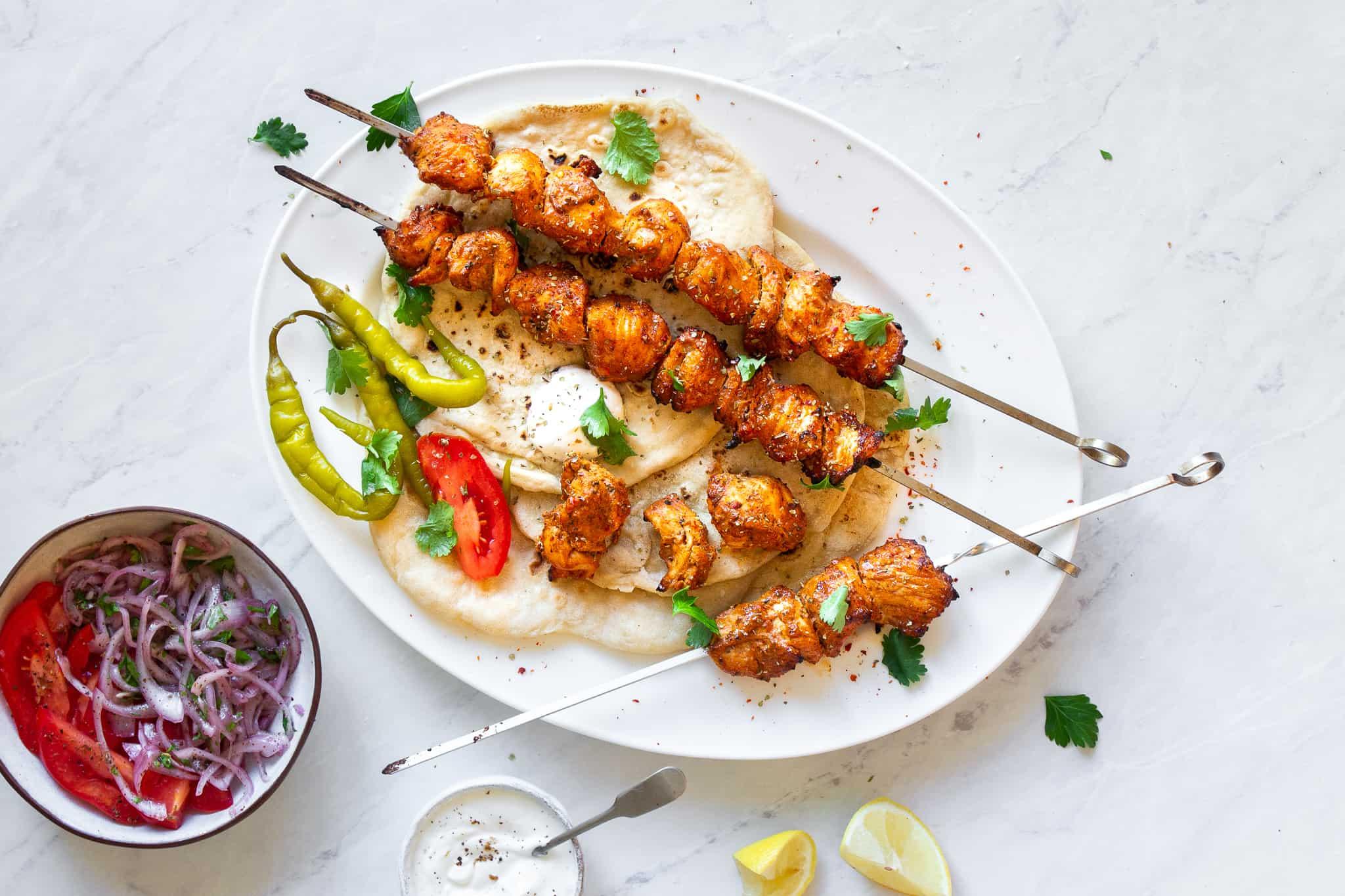 A vibrant image showing the finished chicken shish kebabs glistening with pomegranate glaze, garnished with fresh herbs and lemon wedges.