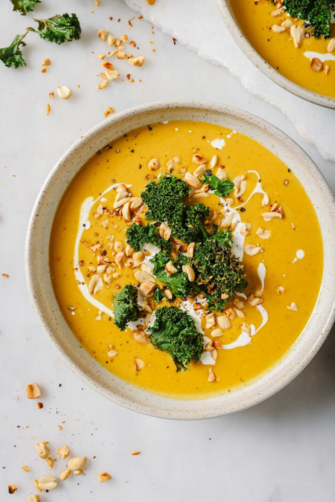 bowl of pumpkin and sweet potato soup with curry powder and coconut milk garnish